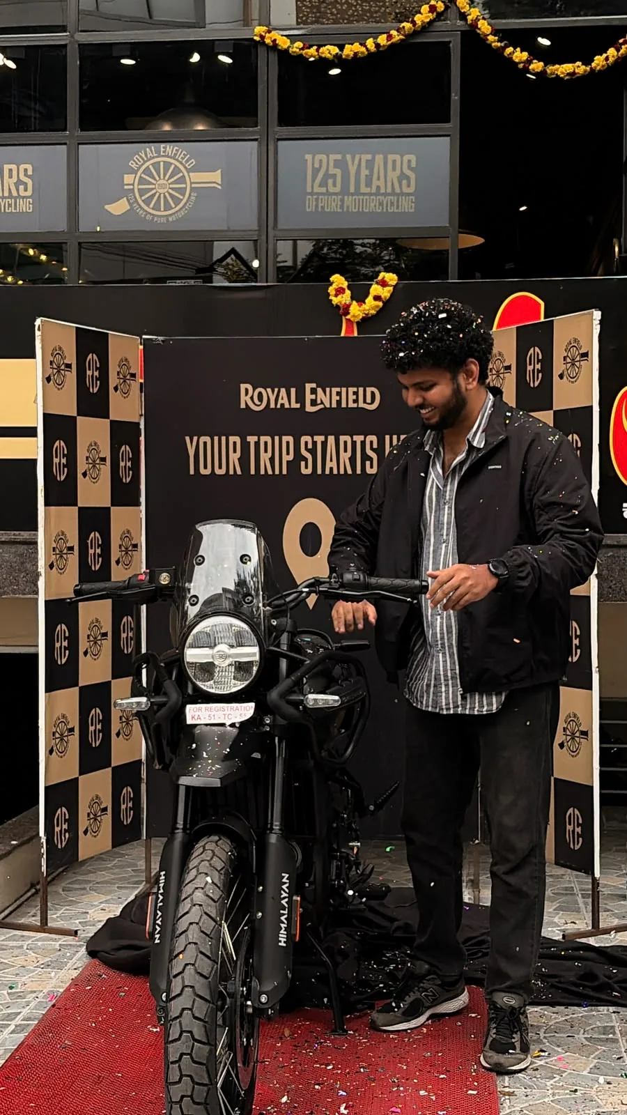 Alvin smiling beside his Royal Enfield motorcycle